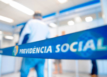 Fila de atendimento em agência do INSS com foco em faixa de isolamento com o nome Previdência Social.