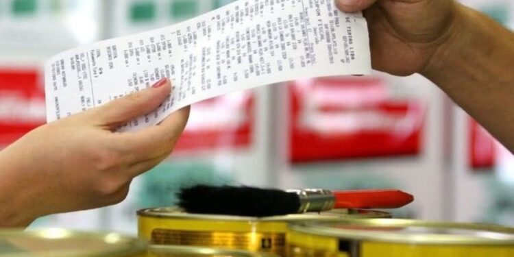 Pessoa recebendo uma nota fiscal de compra em loja de tintas