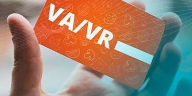 Pessoa segurando um cartão de vale-alimentação ou vale-refeição com fundo laranja, indicando possível mudança no modelo de pagamento.