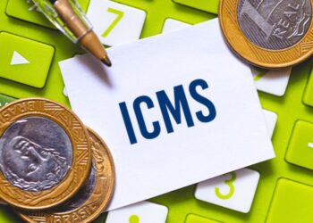 Imagem de moedas e calculadora com a palavra ICMS destacada.