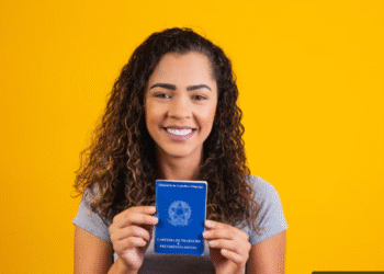 Jovem segurando a Carteira de Trabalho com sorriso no rosto, representando esperança no mercado de trabalho formal.