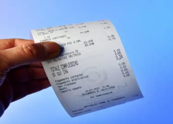 Pessoa segurando nota fiscal detalhada contra fundo azul