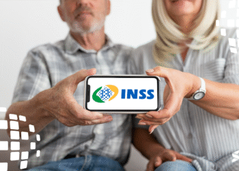 Casal idoso segurando um celular com o logo do INSS na tela, representando a solicitação de aposentadoria pela plataforma online.
