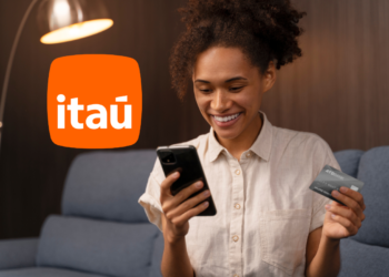 Mulher usando o aplicativo do Itaú para verificar informações com cartão em mãos.