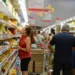 "Pessoas fazendo compras em supermercado, ilustrando a redução nos preços dos alimentos."