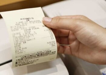 Pessoa retirando um cupom fiscal de uma impressora de recibos.