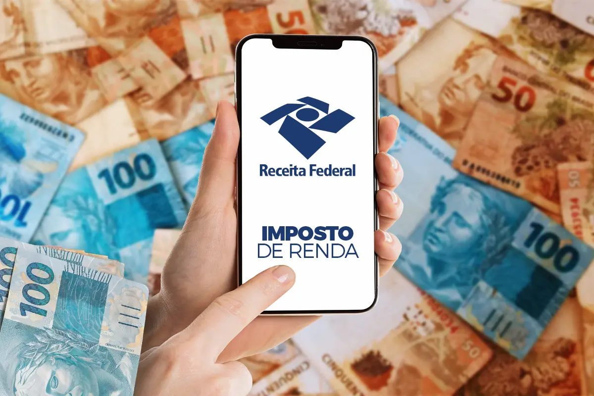 Pessoa consultando a restituição do Imposto de Renda no celular, com cédulas de reais ao fundo.