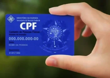 Cartão do CPF sendo segurado por uma mão com fundo desfocado