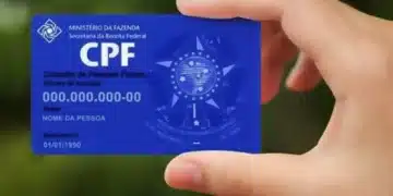 Cartão do CPF sendo segurado por uma mão com fundo desfocado