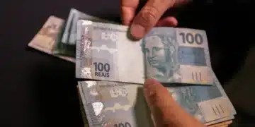 Cédulas de 100 reais sendo contadas, representando a importância do Devolve ICMS 2025.