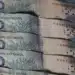 Notas de R$ 100,00 empilhadas, simbolizando o valor de devolução do ICMS Linha Branca, até R$ 1.500.