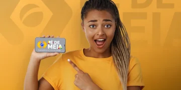 Jovem estudante surpresa aponta para celular com anúncio do resultado do Pé-de-Meia