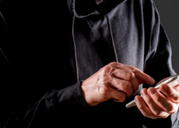 Homem usando o celular para aplicar golpes, representando as fraudes de indenização.