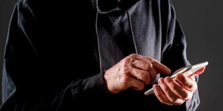 Homem usando o celular para aplicar golpes, representando as fraudes de indenização.