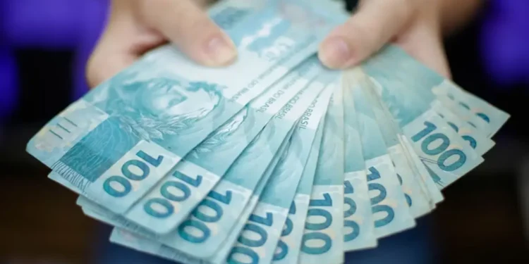 Mãos segurando cédulas de R$100 representando a premiação do programa Nota da Gente