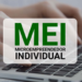 Mãos digitando em notebook com destaque para a sigla MEI - Microempreendedor Individual.