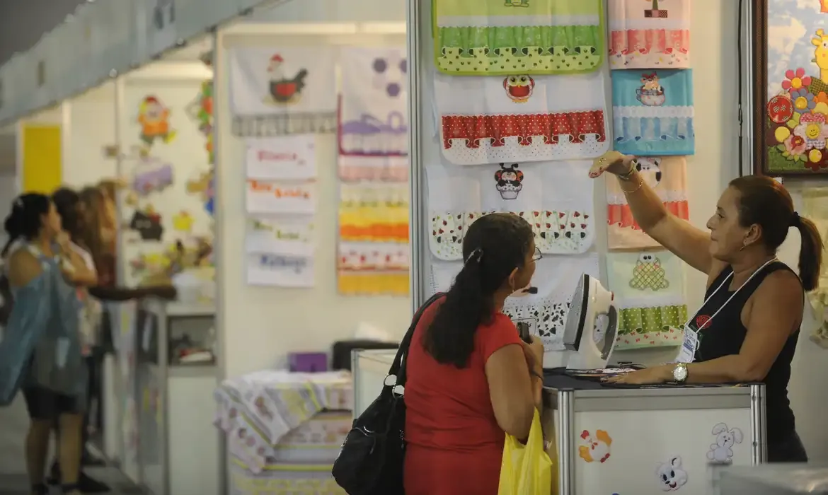 Pessoas interagindo em um estande de feira, discutindo sobre produtos e possibilidades de negócio, ilustrando atividades empreendedoras.