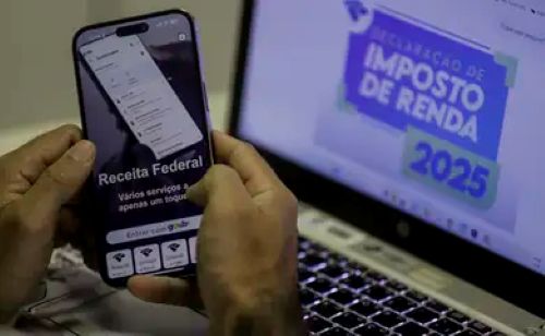Pessoa acessando a Receita Federal pelo celular com fundo do Imposto de Renda 2025