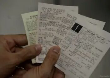 "Pessoa segurando várias notas fiscais, representando o sorteio do Nota Legal, que pode premiar com até R$ 1 milhão."