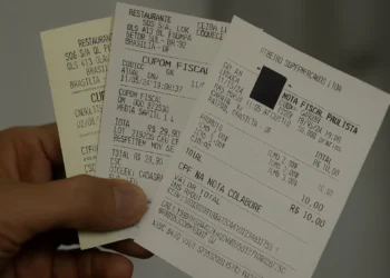 Pessoa segurando um cupom fiscal com CPF na nota