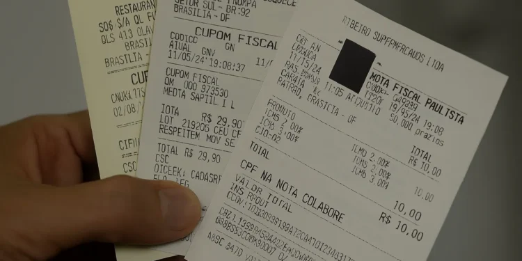 Pessoa segurando um cupom fiscal com CPF na nota