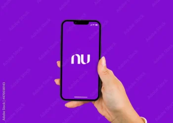 Mão segurando um smartphone exibindo o logotipo do Nubank com um fundo roxo.