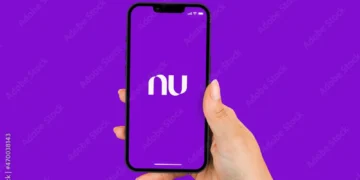 Mão segurando um smartphone exibindo o logotipo do Nubank com um fundo roxo.