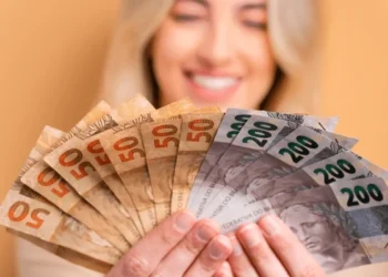 mulher sorrindo ao exibir notas de real, simbolizando os prêmios do cpf premiado