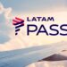 Logo do programa LATAM Pass com fundo de asa de avião em voo e céu ao entardecer