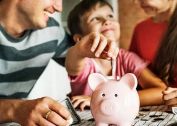 Família colocando moedas em um cofrinho, simbolizando economia e o suporte do Salário-Família.