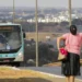 "Mulher aguardando um ônibus, simbolizando o benefício de transporte gratuito para mães."