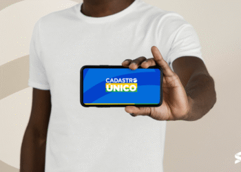 Pessoa segura um celular com a tela exibindo o logotipo do Cadastro Único, informando sobre a atualização cadastral obrigatória.