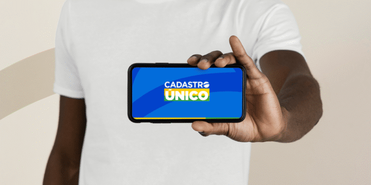 Pessoa segura um celular com a tela exibindo o logotipo do Cadastro Único, informando sobre a atualização cadastral obrigatória.