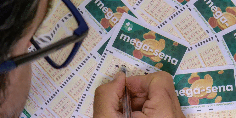 Imagem de um apostador preenchendo seu bilhete da Mega-Sena, com vários cupons em cima da mesa, representando a chance de ganhar o prêmio acumulado deste sábado.