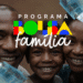 Família sorridente representando beneficiários do programa Bolsa Família, com cédulas de reais ao fundo.