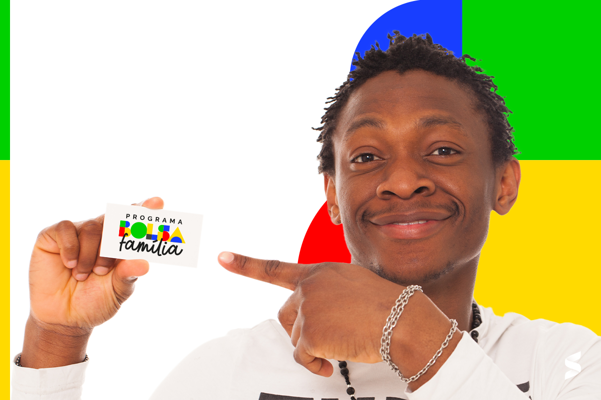Homem sorridente aponta para cartão do Bolsa Família com fundo colorido