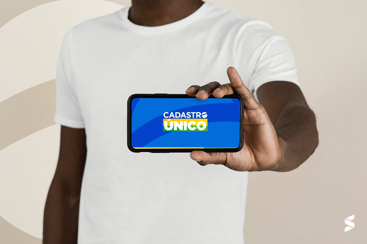 Pessoa segurando celular com a tela exibindo a logo do Cadastro Único