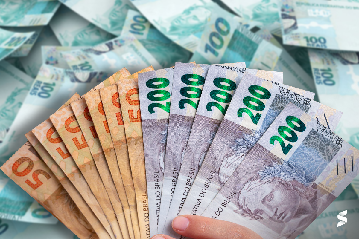 Mão segurando várias cédulas de reais, destacando a importância do Abono Salarial PIS/Pasep como reforço financeiro.