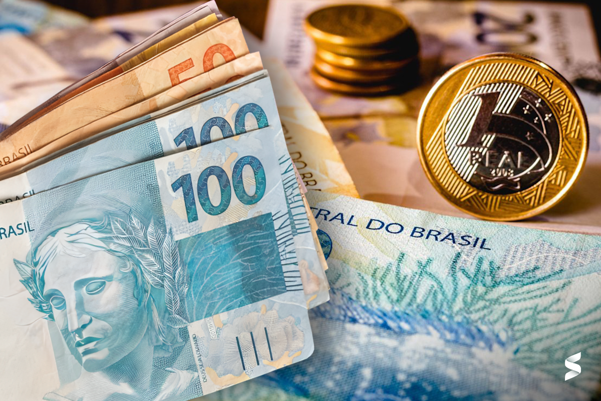 Imagem ilustrativa com notas e moedas em reais, representando o pagamento do Auxílio Gás.