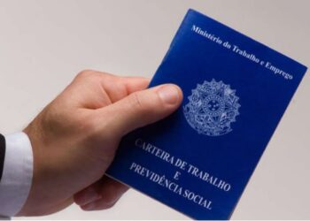 Mão segurando carteira de trabalho e previdência social