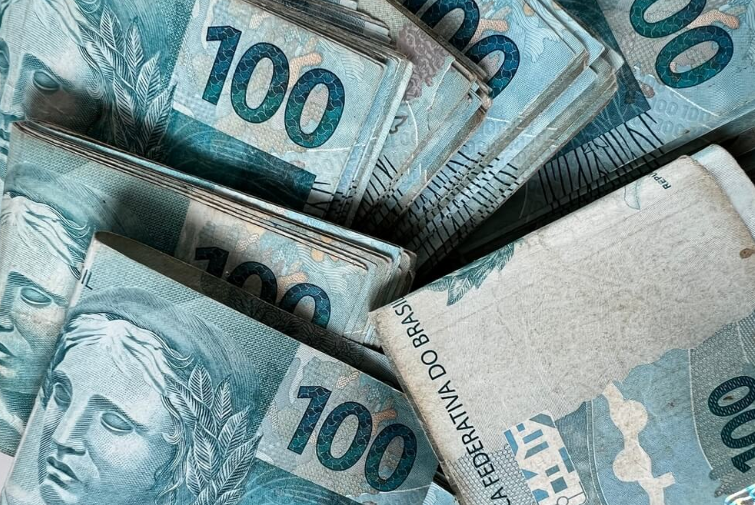 Pilhas de cédulas de R$100, representando a discussão sobre o salário mínimo no Brasil e suas possíveis mudanças em 2026.