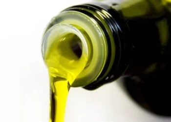 Azeite extraído de uma garrafa escura, mostrando o líquido dourado sendo despejado.
