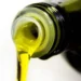 Azeite extraído de uma garrafa escura, mostrando o líquido dourado sendo despejado.