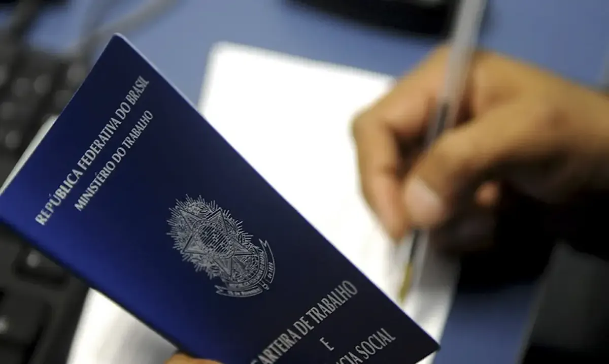 Pessoa assinando a carteira de trabalho, representando o processo de formalização para solicitar a antecipação de salário.
