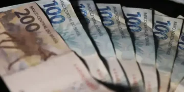 Cédulas de 100 e 200 reais em mãos, representando o processo de antecipação de salário via PIX