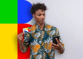 "Jovem segurando o cartão do Bolsa Família e um celular, simbolizando o processo de consulta ao valor do benefício."