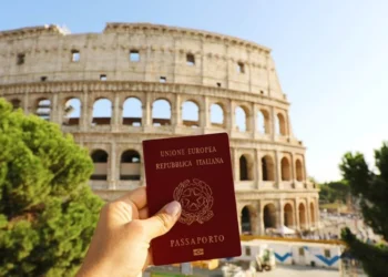 Passaporte italiano segurado em frente ao Coliseu, em Roma.