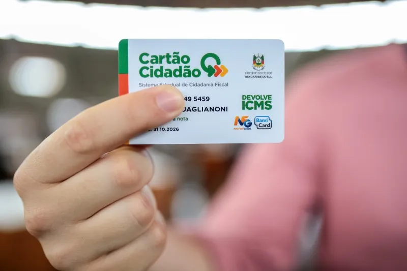 Pessoa segurando o Cartão Cidadão do Devolve ICMS, um programa do governo do Rio Grande do Sul.
