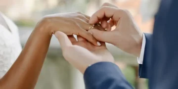 Pessoa colocando aliança no dedo durante cerimônia de casamento.