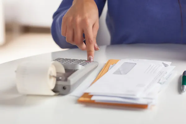 Pessoa usando calculadora para organizar finanças e controlar dívidas